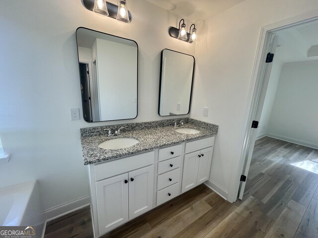 bathroom with hardwood / wood-style flooring, a bath, and vanity