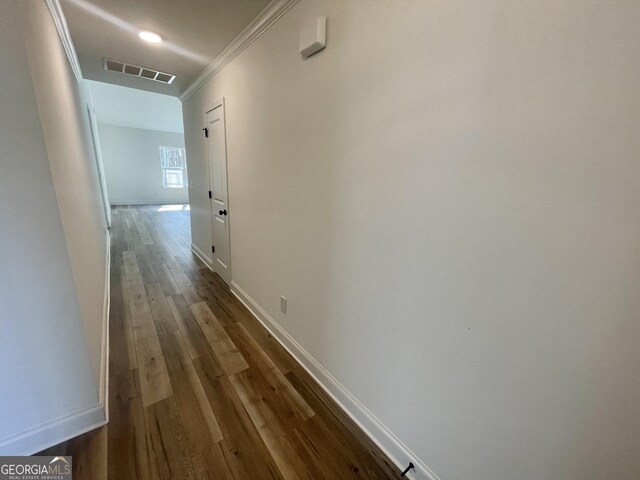 empty room with crown molding, dark wood-type flooring, and a raised ceiling