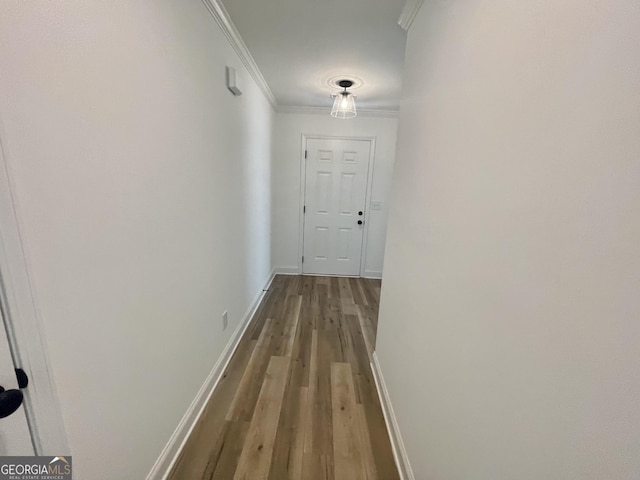 hall featuring ornamental molding, baseboards, and wood finished floors