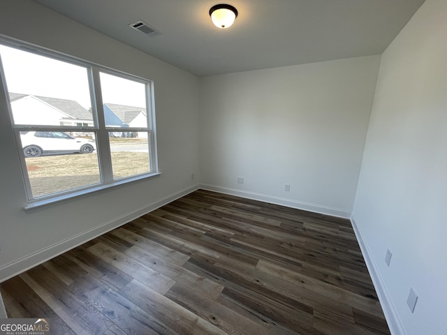 spare room with dark hardwood / wood-style floors and plenty of natural light