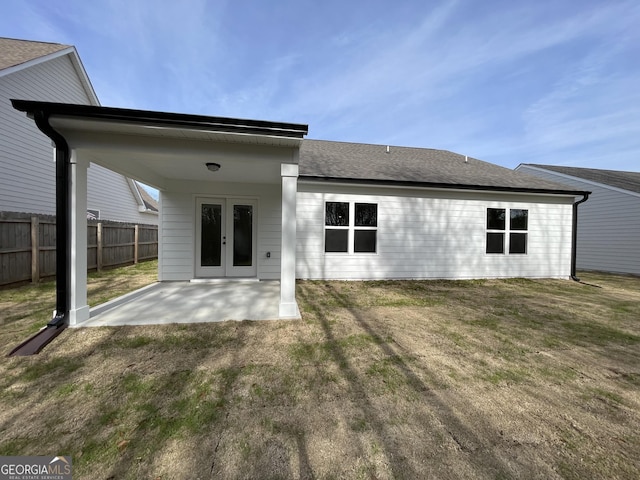 back of house featuring a shingled roof, a lawn, a patio area, and fence