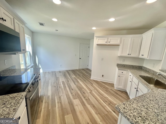 kitchen featuring visible vents, appliances with stainless steel finishes, white cabinetry, a sink, and light stone countertops