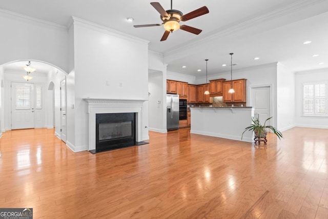 unfurnished living room featuring ceiling fan, light hardwood / wood-style flooring, and ornamental molding