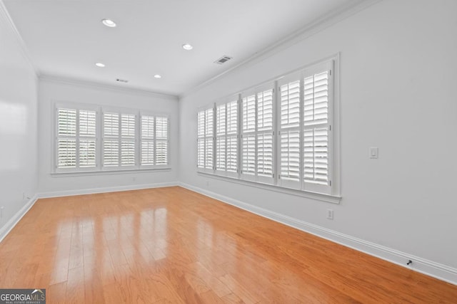 spare room with crown molding, a healthy amount of sunlight, and light hardwood / wood-style floors