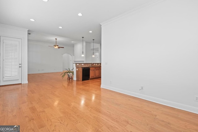 unfurnished living room featuring sink, light wood-type flooring, ceiling fan, and ornamental molding