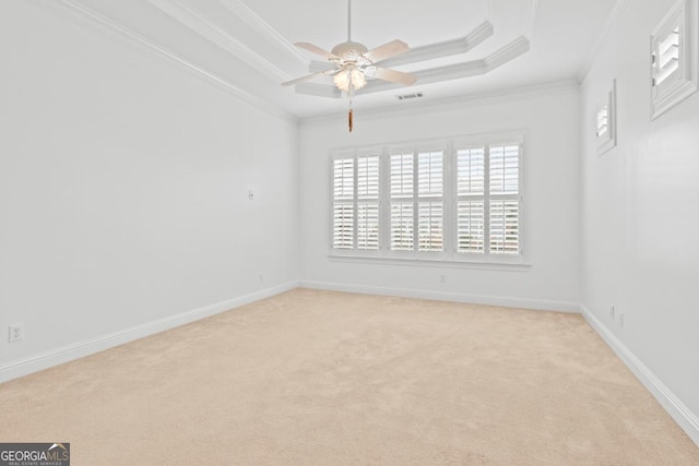 spare room featuring ceiling fan, a raised ceiling, ornamental molding, and light colored carpet