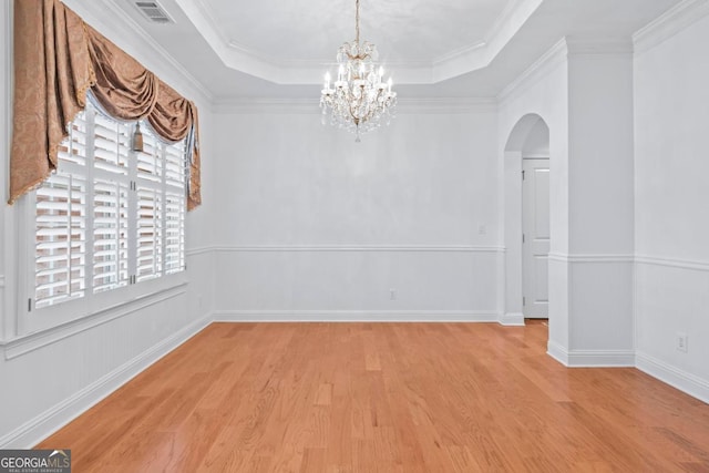 unfurnished room with crown molding, light wood-type flooring, and a tray ceiling