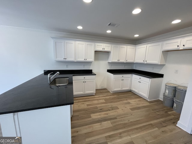 kitchen with sink, white cabinets, hardwood / wood-style flooring, and ornamental molding