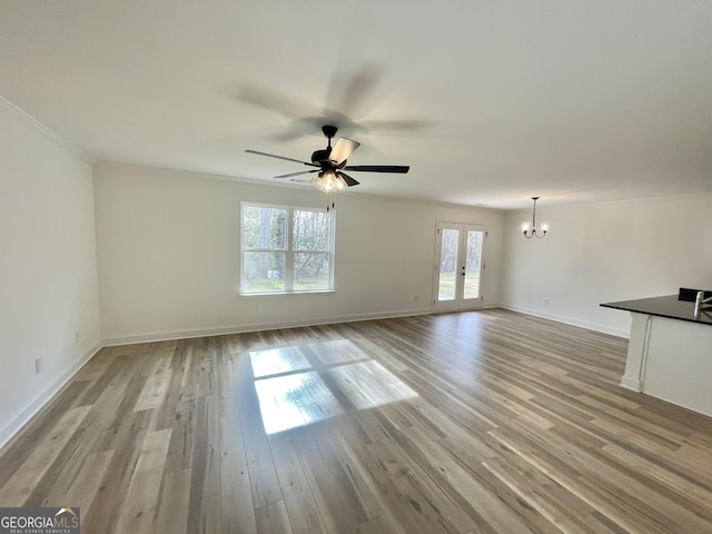 unfurnished living room featuring light wood-type flooring, french doors, baseboards, and ceiling fan with notable chandelier