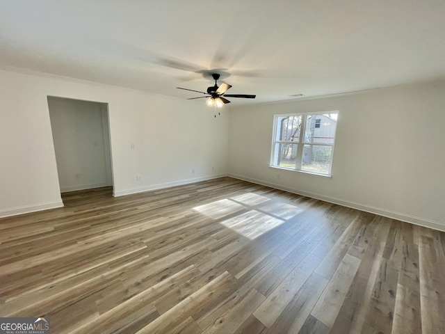 unfurnished room featuring light wood finished floors, baseboards, and a ceiling fan