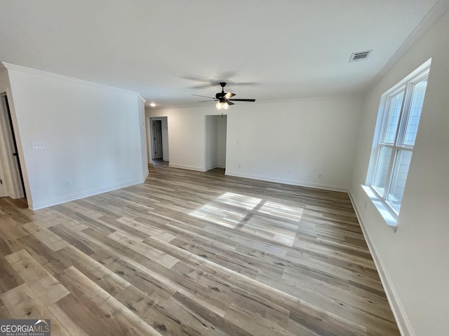 empty room featuring ornamental molding, light wood finished floors, visible vents, and baseboards