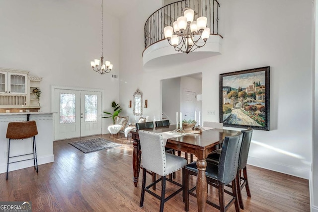 dining room featuring a high ceiling, dark hardwood / wood-style floors, an inviting chandelier, and french doors