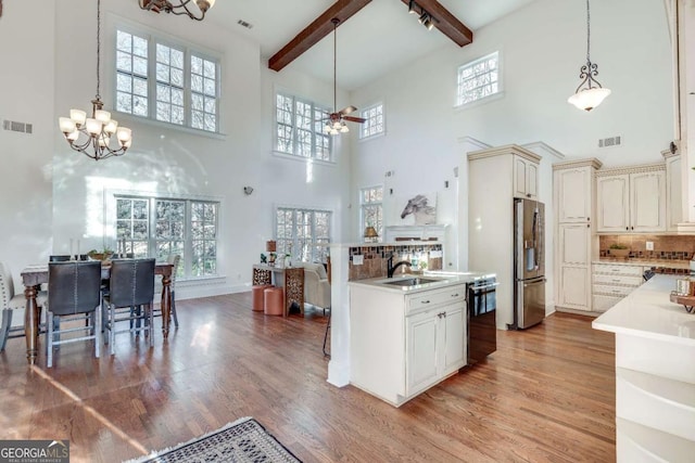 kitchen with sink, dishwasher, beam ceiling, stainless steel fridge with ice dispenser, and light wood-type flooring