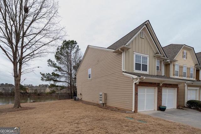 view of home's exterior featuring central AC unit, a garage, and a water view