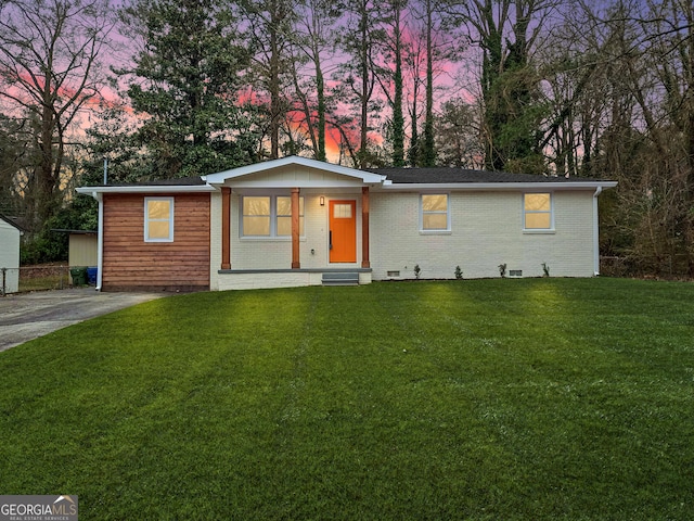 single story home featuring a lawn and brick siding