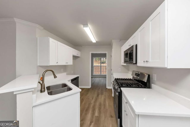 kitchen featuring sink, kitchen peninsula, white cabinets, and stainless steel appliances