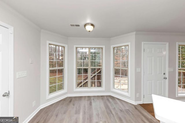 unfurnished dining area with crown molding and light wood-type flooring