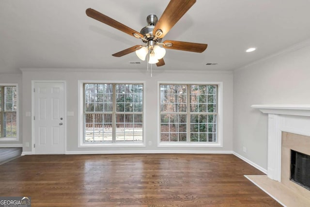 unfurnished living room featuring dark hardwood / wood-style flooring, crown molding, plenty of natural light, and a fireplace