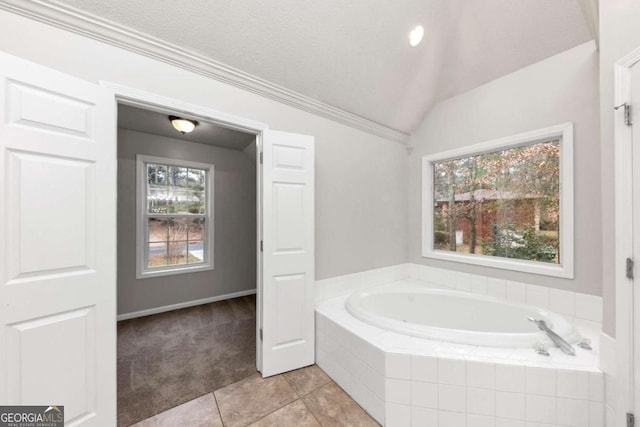 bathroom featuring tiled tub, ornamental molding, lofted ceiling, and tile patterned flooring