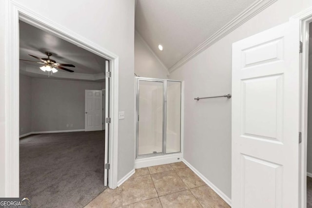 bathroom with a shower with shower door, tile patterned floors, vaulted ceiling, ceiling fan, and crown molding