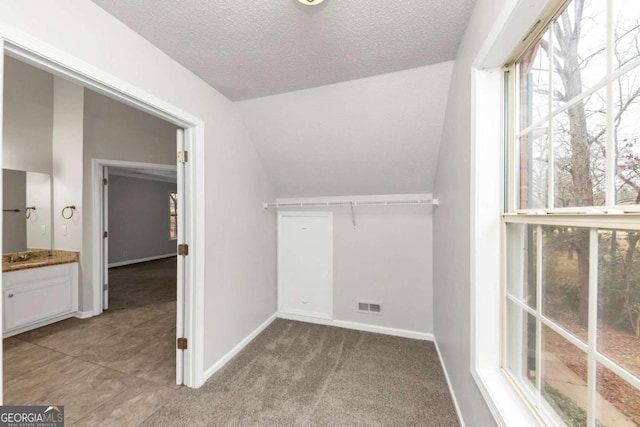 spacious closet with light colored carpet and vaulted ceiling