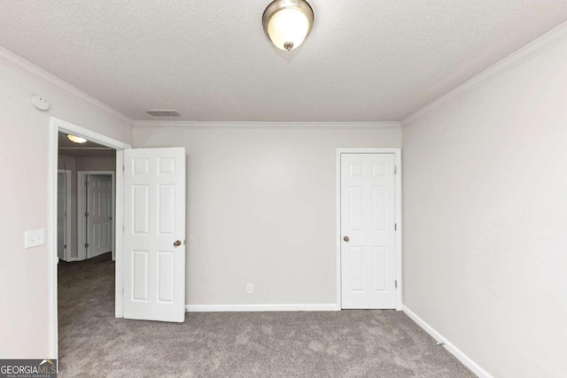 empty room with a textured ceiling, ornamental molding, and carpet flooring