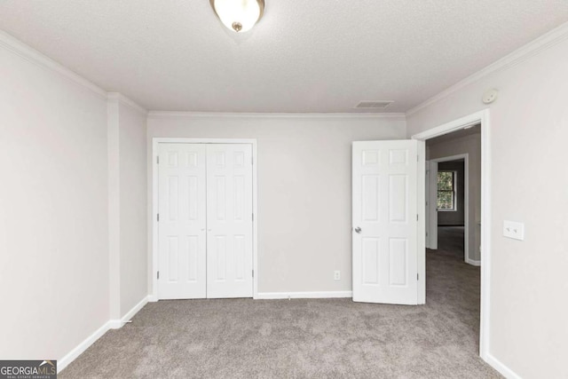 unfurnished bedroom featuring crown molding, a closet, light carpet, and a textured ceiling