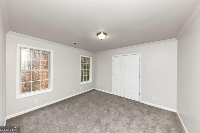 unfurnished bedroom featuring a closet, ornamental molding, and dark colored carpet