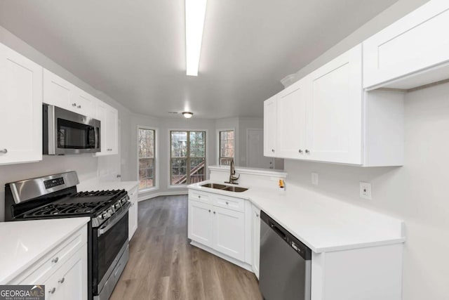 kitchen featuring kitchen peninsula, light hardwood / wood-style flooring, sink, white cabinets, and stainless steel appliances