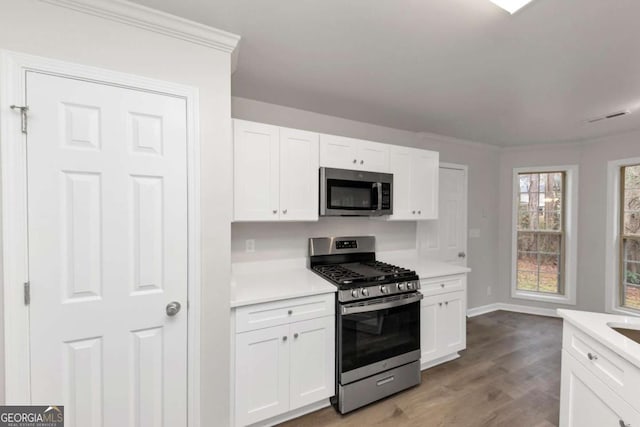 kitchen with light hardwood / wood-style floors, white cabinetry, and appliances with stainless steel finishes