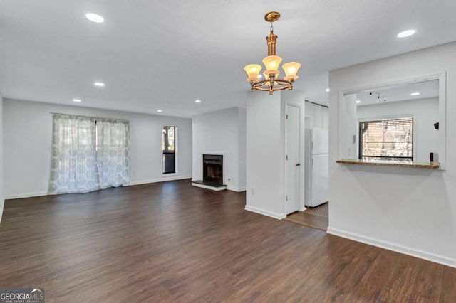 unfurnished living room featuring a notable chandelier and dark hardwood / wood-style flooring