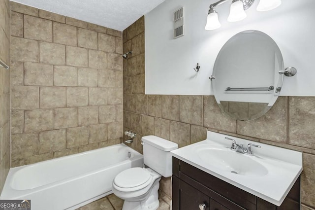 full bathroom featuring tile walls, tiled shower / bath, a textured ceiling, toilet, and vanity