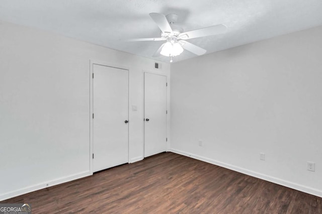 unfurnished bedroom featuring ceiling fan and dark hardwood / wood-style flooring