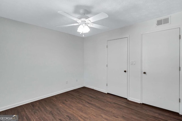 unfurnished bedroom with ceiling fan, dark wood-type flooring, and a textured ceiling