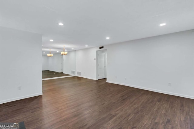 unfurnished living room with a chandelier and dark hardwood / wood-style floors