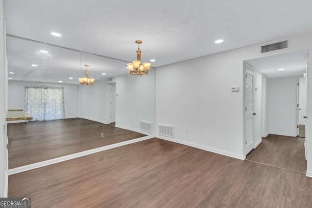 spare room with a chandelier and dark hardwood / wood-style floors