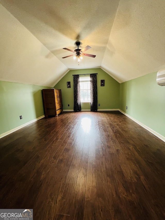 additional living space featuring wood-type flooring, ceiling fan, a wall mounted air conditioner, a textured ceiling, and lofted ceiling