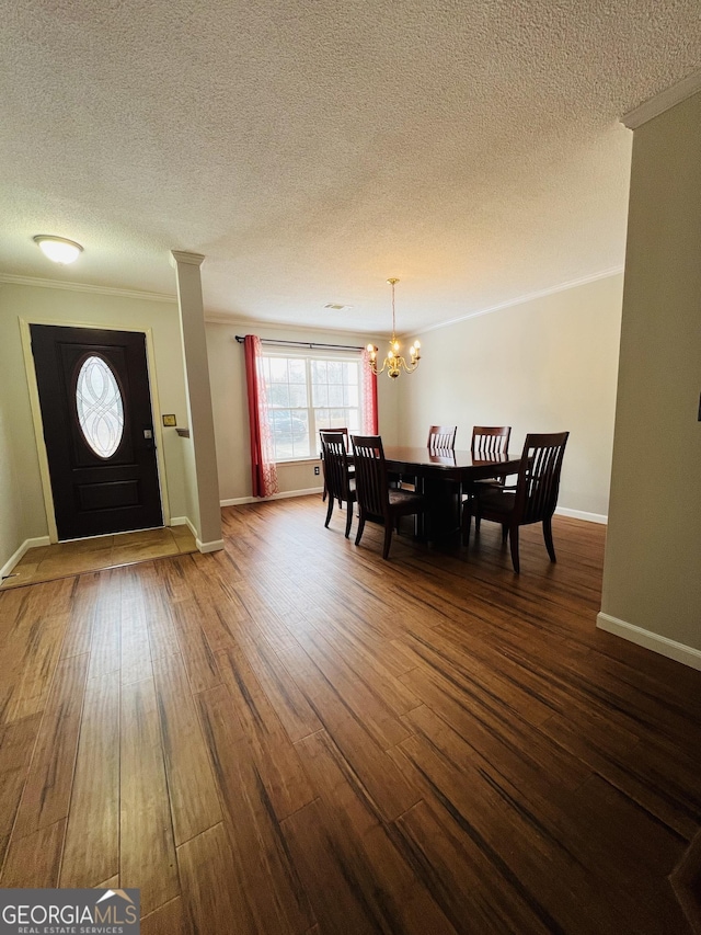 dining room featuring a textured ceiling, dark hardwood / wood-style floors, crown molding, and a notable chandelier