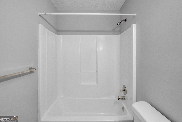 bathroom with shower / tub combination, a textured ceiling, and toilet