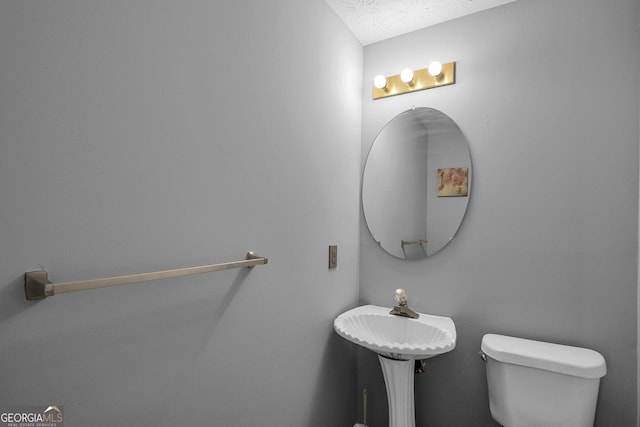 bathroom with toilet, sink, and a textured ceiling