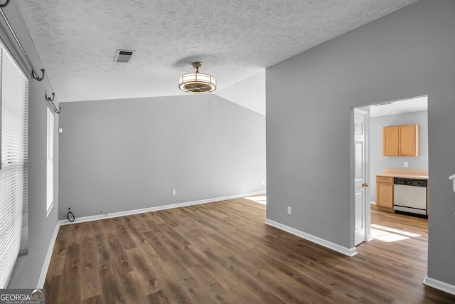 spare room featuring vaulted ceiling, a textured ceiling, and dark hardwood / wood-style flooring