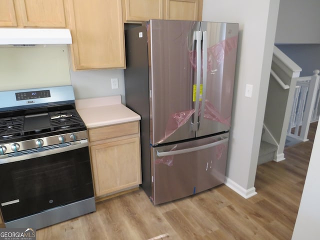 kitchen with light brown cabinetry, stainless steel appliances, and light wood-type flooring