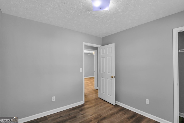 unfurnished bedroom featuring a textured ceiling and dark hardwood / wood-style flooring