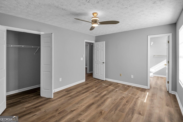 unfurnished bedroom with ceiling fan, dark hardwood / wood-style floors, a textured ceiling, and a closet