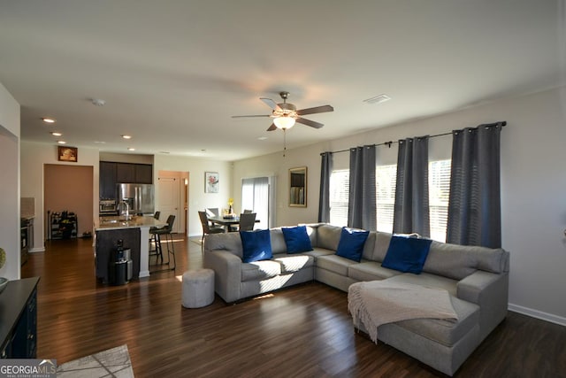 living room featuring dark wood-type flooring and ceiling fan