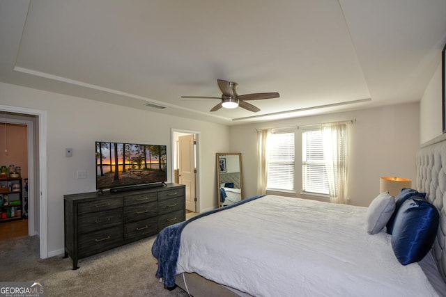 bedroom with light carpet, a tray ceiling, and ceiling fan