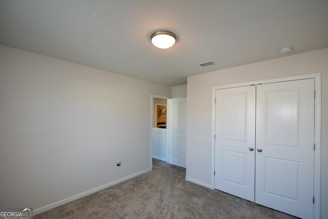 unfurnished bedroom with light colored carpet and a closet