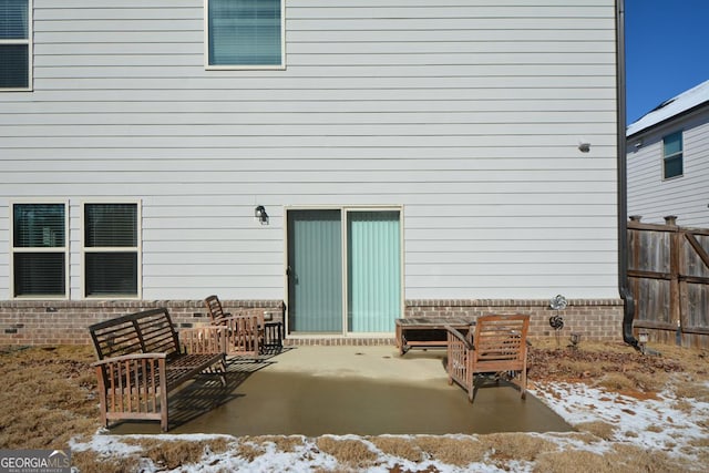 snow covered rear of property with a patio area