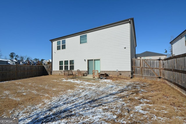 snow covered rear of property featuring a patio