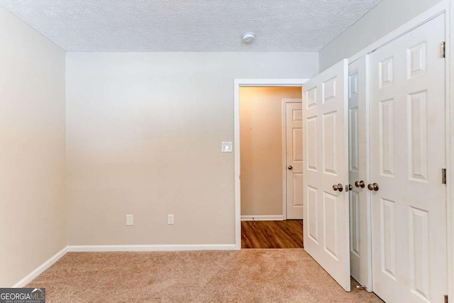 unfurnished room featuring a textured ceiling and carpet